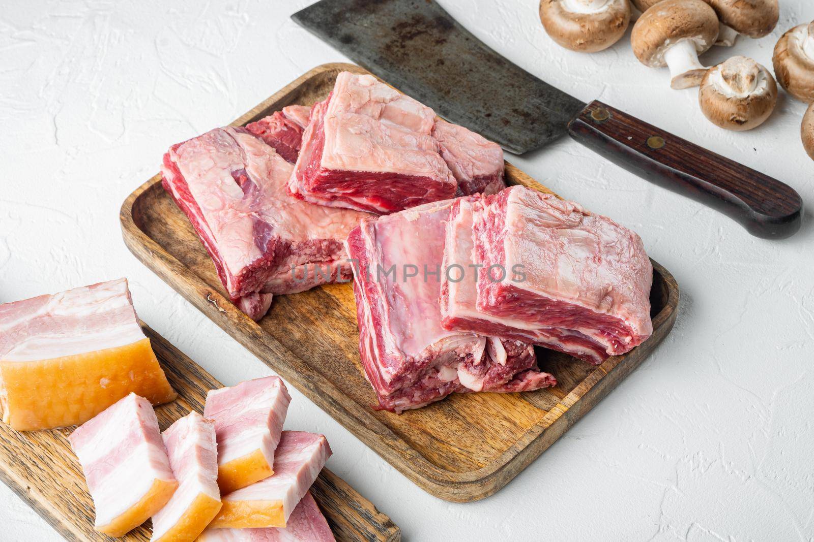 Raw Black Angus Marbled Beef Ribs set, with ingredients, and old butcher cleaver knife, on white stone background