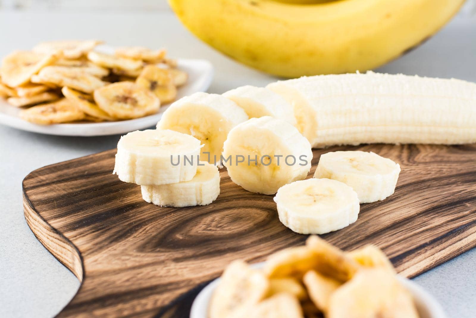 Banana slices on a cutting board for making banana chips on the table. Fast food. by Aleruana