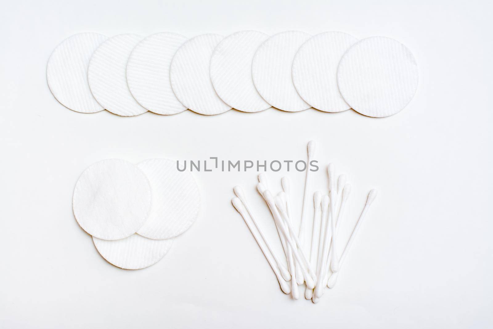 Clean cotton pads and cotton swabs for removing cosmetics on a white background. Top view by Aleruana