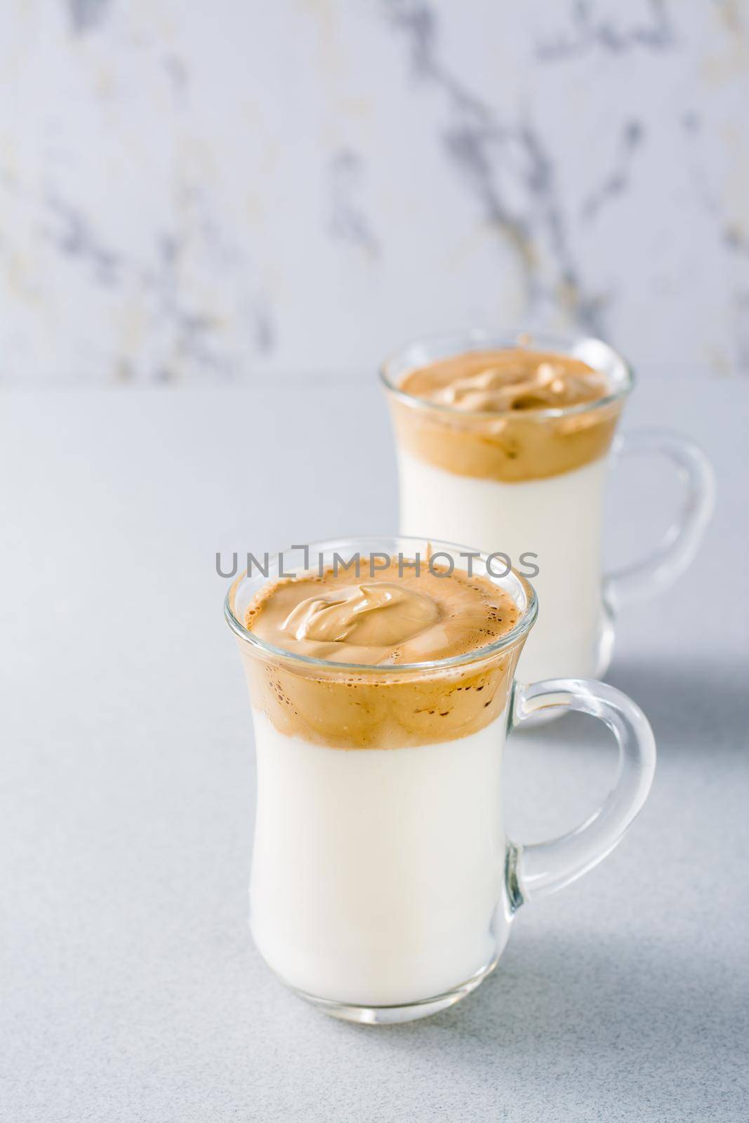 Quarantine trendy cuisine. Two cups with dalgona coffee on a gray background. Vertical view