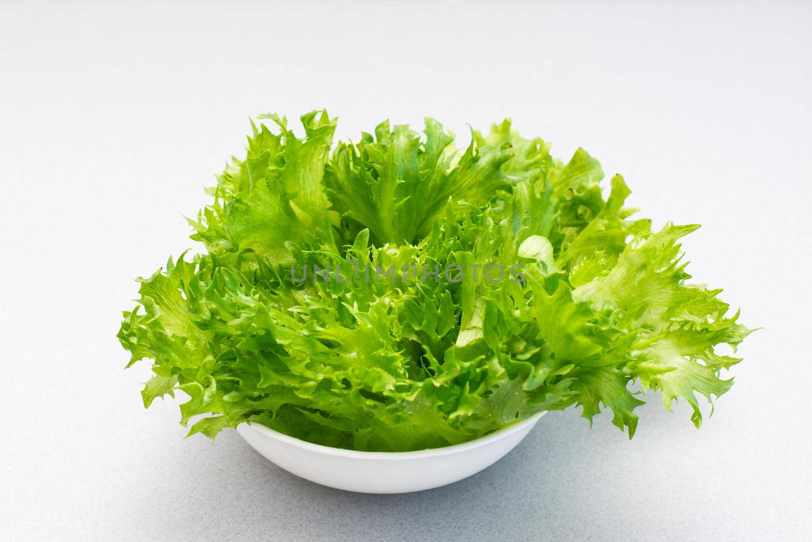 Fresh green lettuce leaves in a bowl on the table. Healthy eating by Aleruana