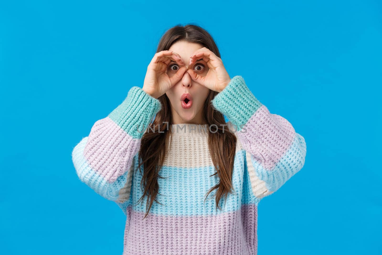Girl found amazing, stunning offer. Amazed speechless and astounded young attractive woman holding hands like binocular over eye, folding lips excited, popping eyse camera impressed, see good promo.
