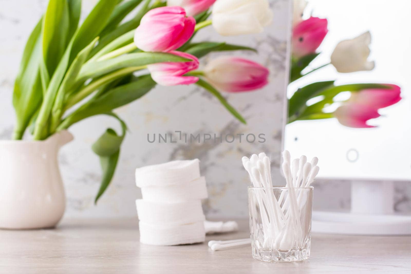 Personal hygiene, cleanliness and skin care. Cotton pads and swabs on the table in front of the mirror. by Aleruana