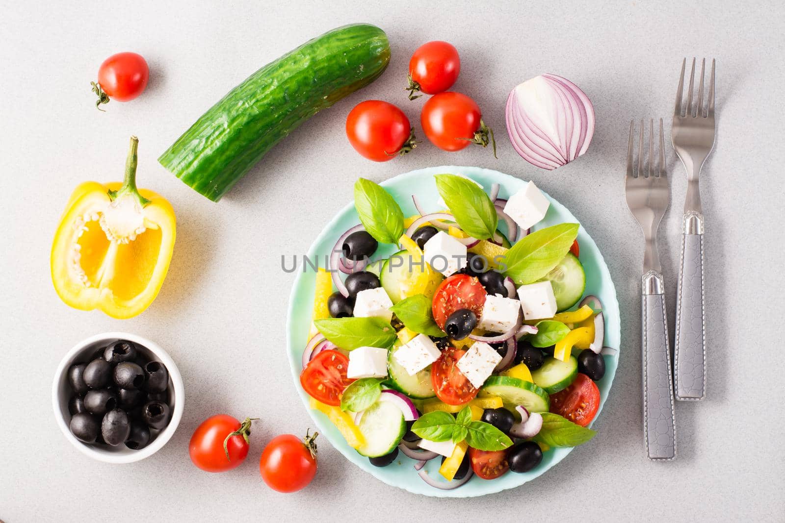Fresh homemade greek salad with basil leaves on a plate and ingredients for cooking on the table. Domestic life. Top view by Aleruana
