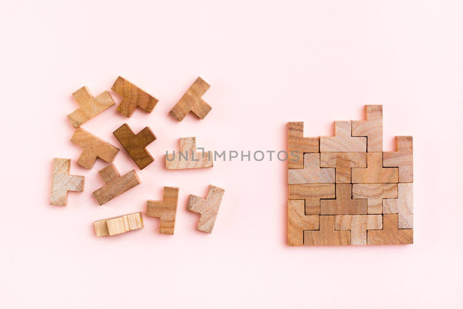 Organization and order. Wooden puzzle pieces are stacked correctly and chaotically scattered in disarray on a pink background