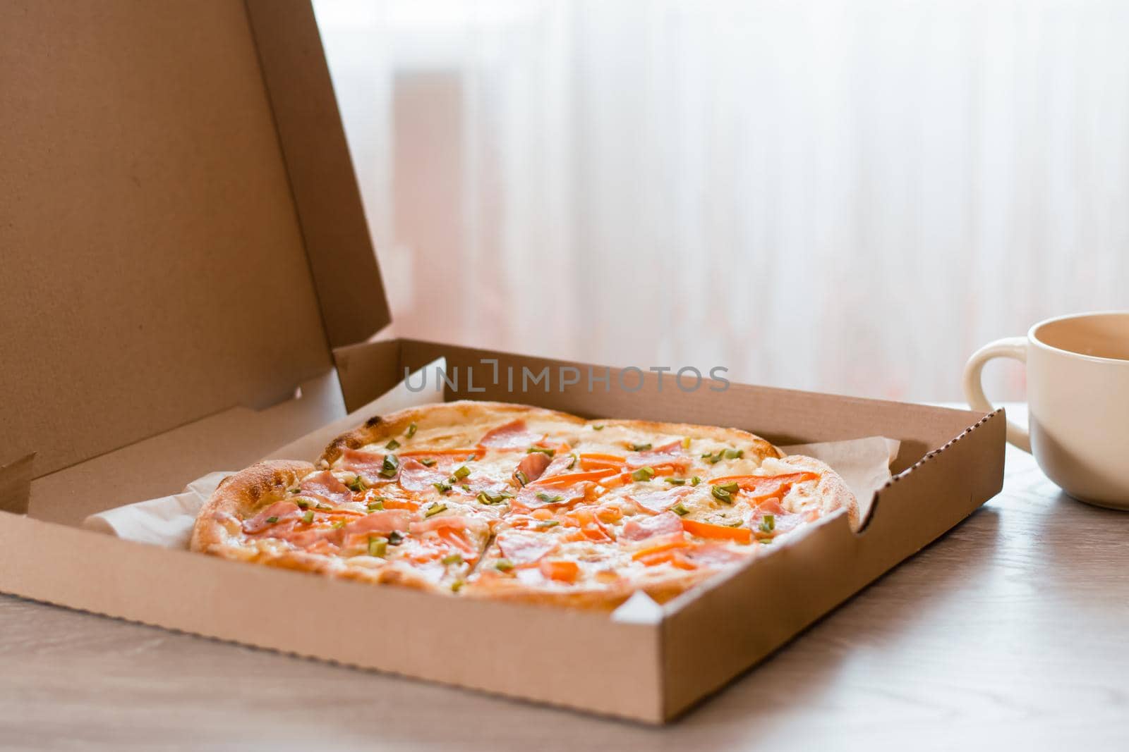Takeaway food. Pizza in a cardboard box on the table in the kitchen.