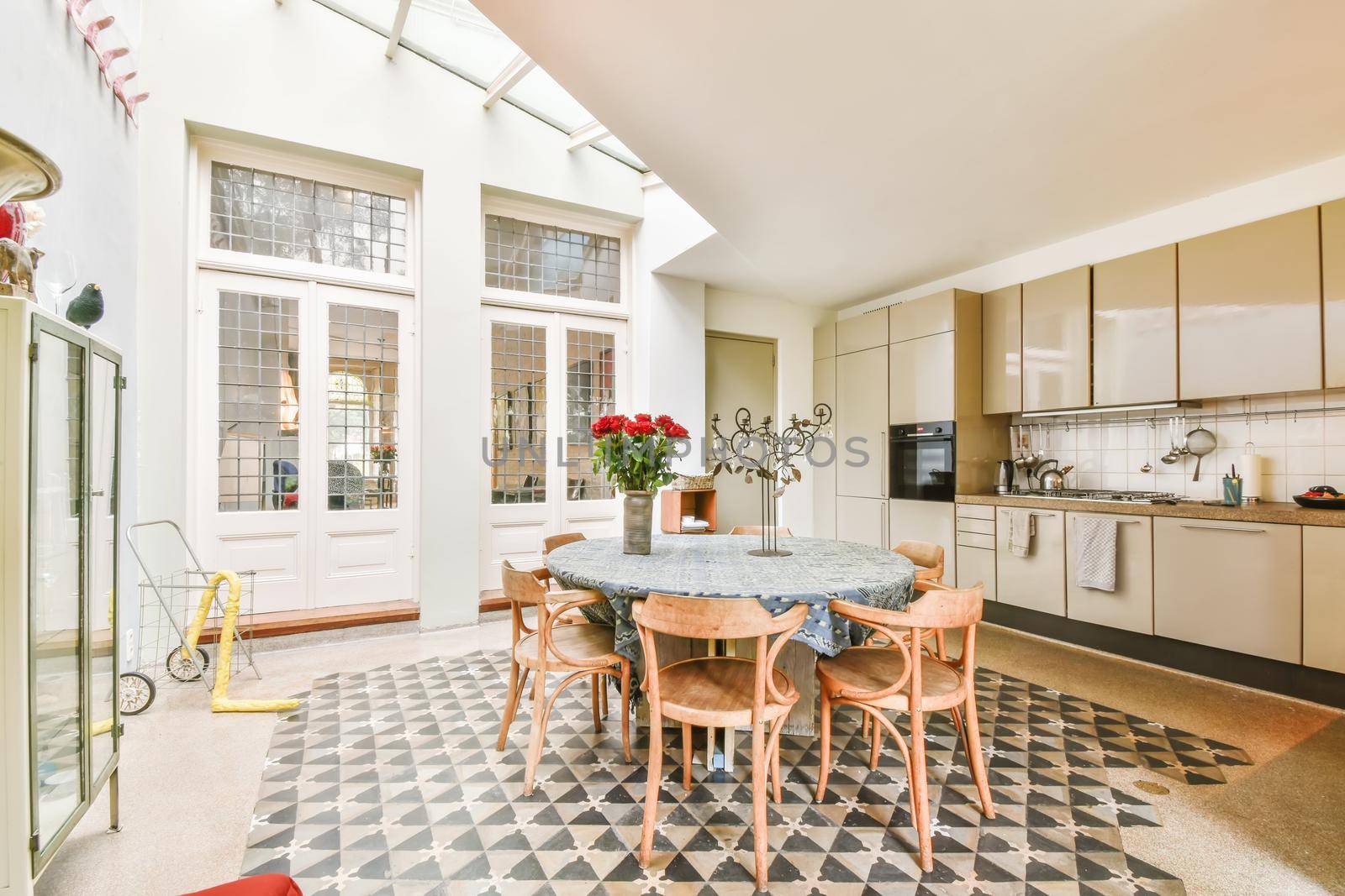 Chic dining room with round table with tablecloth and wooden chairs and black and white floor