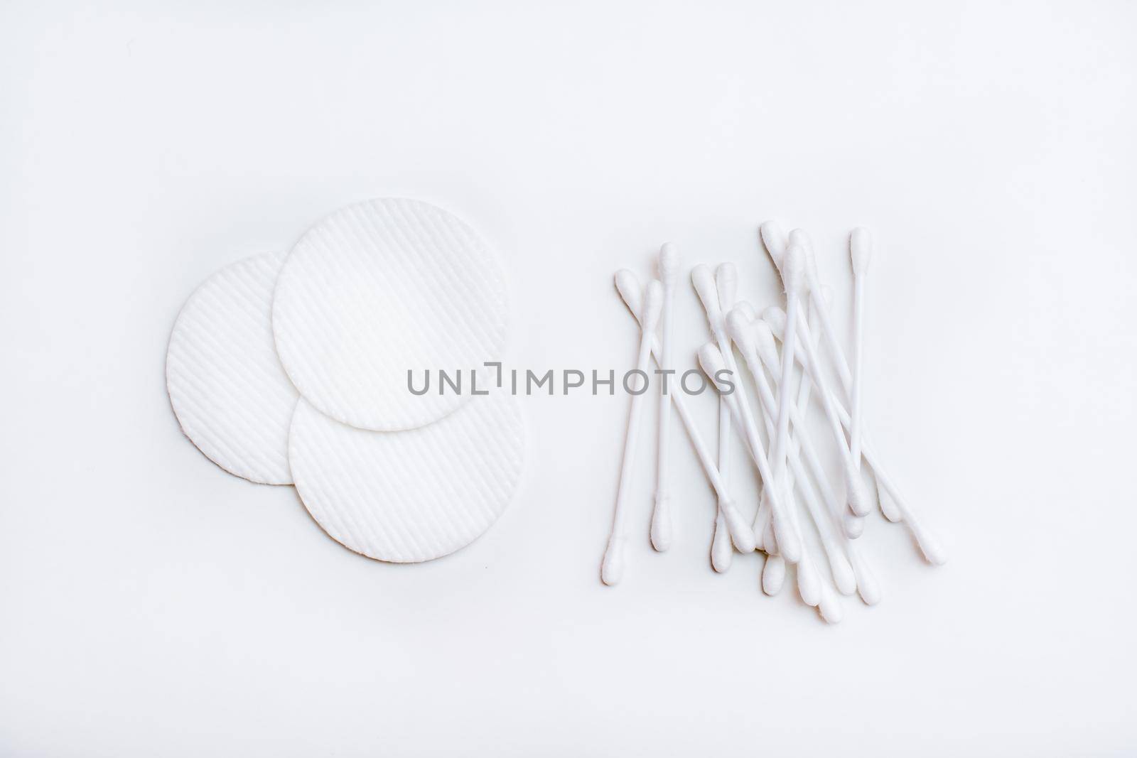 Several clean cotton pads and cotton swabs on a white background. Top view