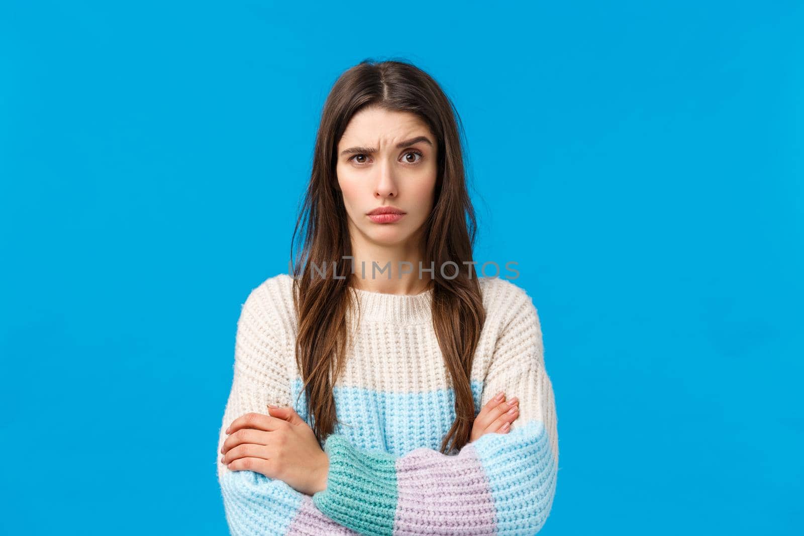 Skeptical, annoyed and displeased young woman hearing something stupid, nonsense, raise eyebrow suspicious and doubtful, cross hands over chest with disapproval, standing blue background.