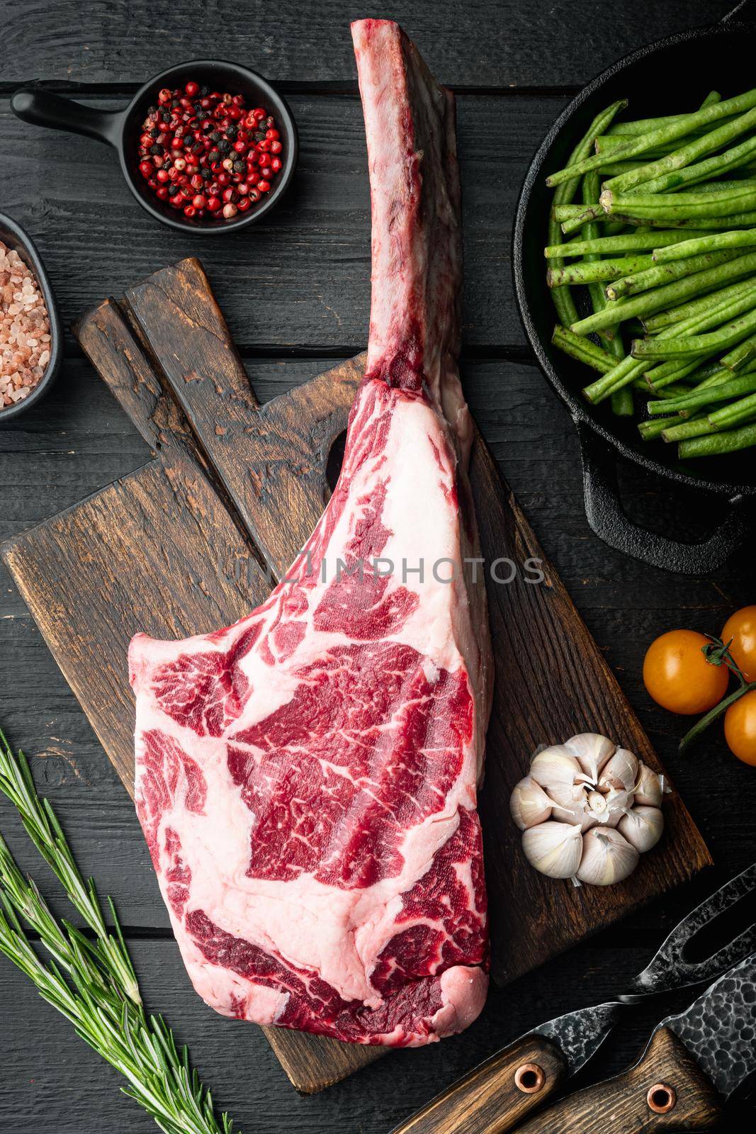 Uncooked raw beef red meat marbled with bone in set, with grill ingredients, on black wooden table background, top view flat lay