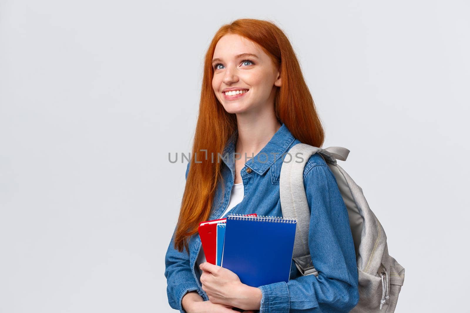 Youth, teenagers and education concept. Determined good-looking dreamy and upbeat smiling redhead female student with notebooks and backpack looking forward new theme in class.