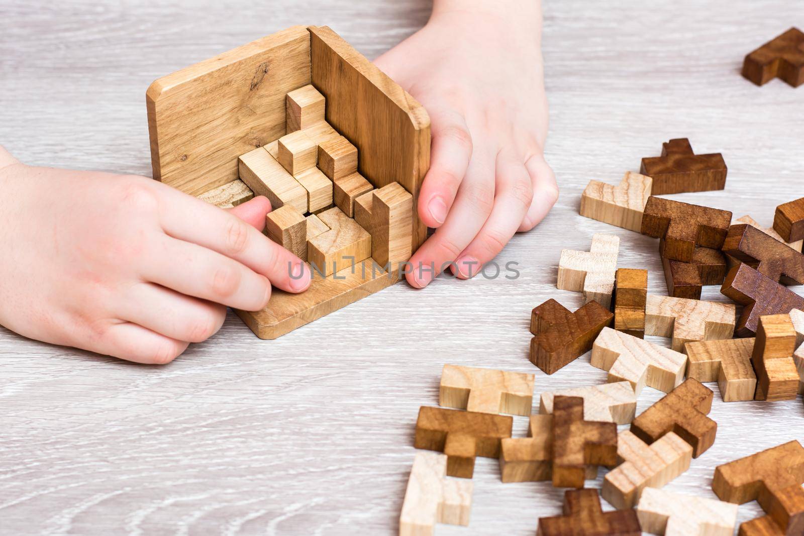 Organization and order. Children's hands fold the wooden puzzle pieces into a folding mold. Leisure for children by Aleruana