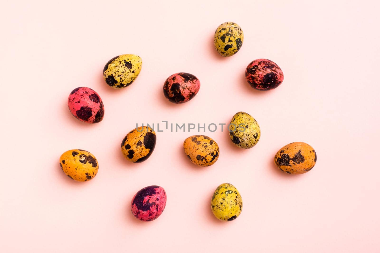 Happy Easter. Painted quail eggs on a pink background
