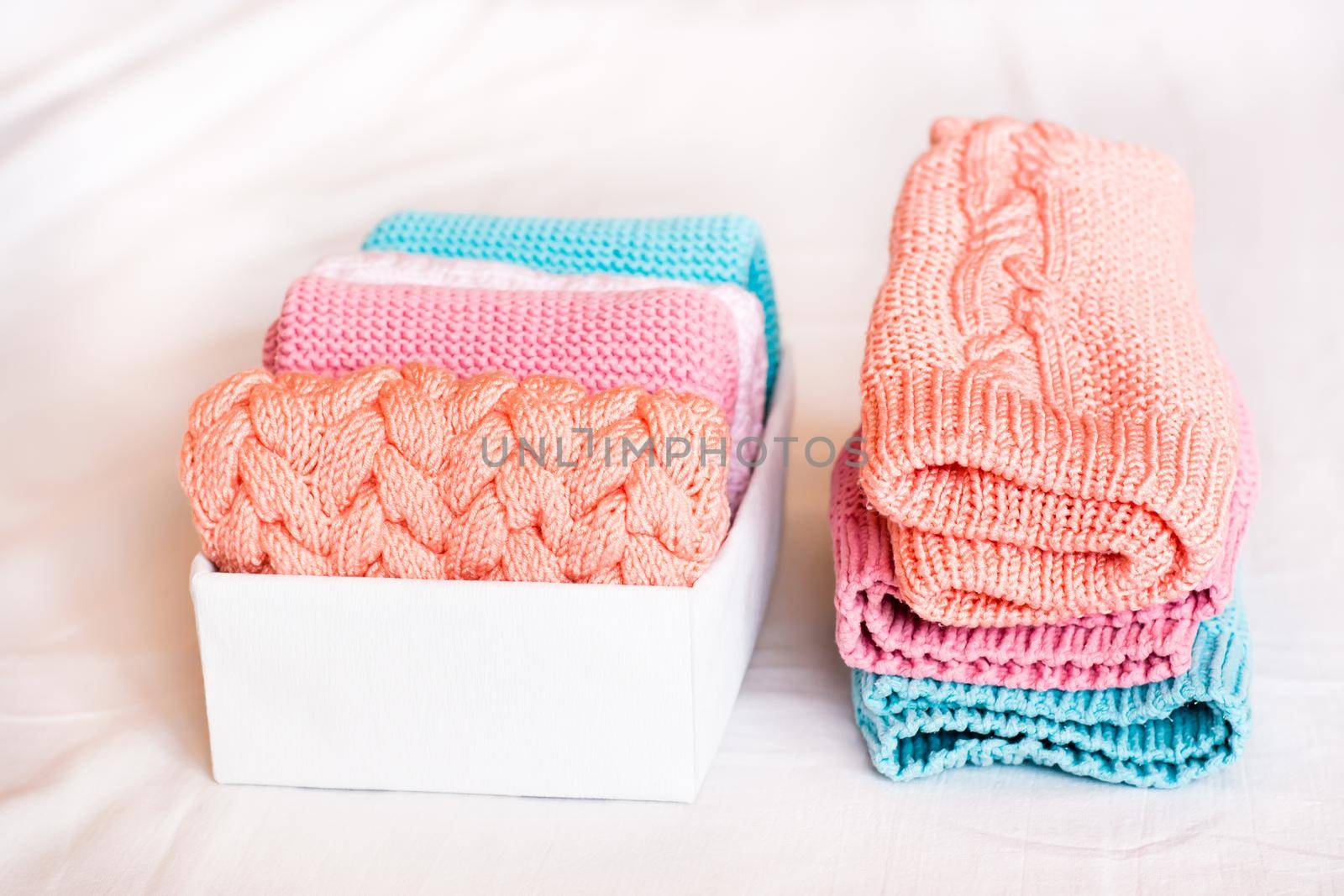 Organization and order. A stack of knitted clothes next to a box of neatly folded items