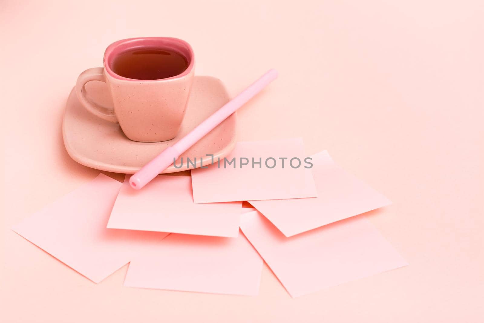 The concept is pink. Pink drink in a coffee cup, writing sheets and pen on a pink background