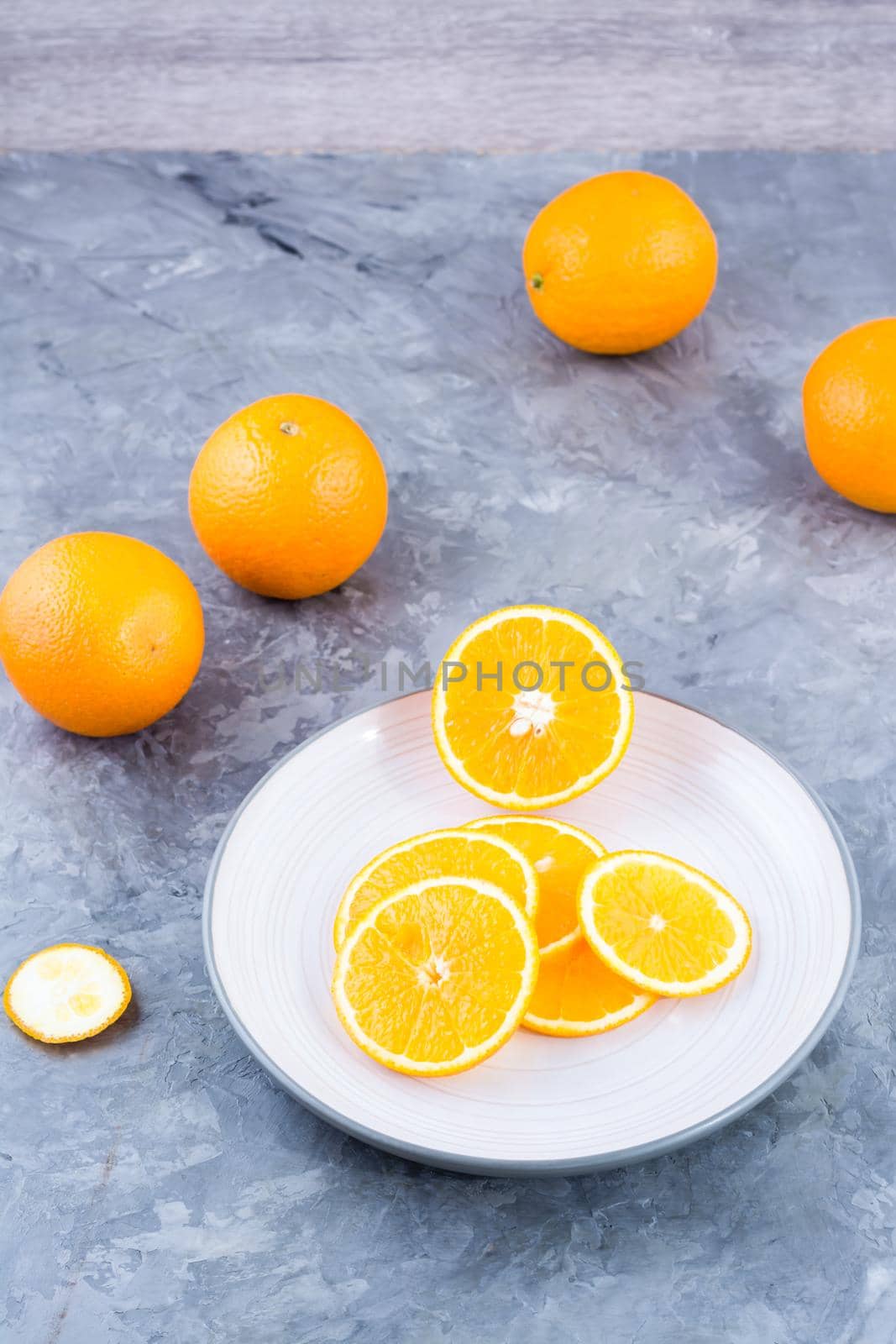 Pieces of fresh orange on a plate on the table. Vitamins, diet and vigor. Vertical view by Aleruana