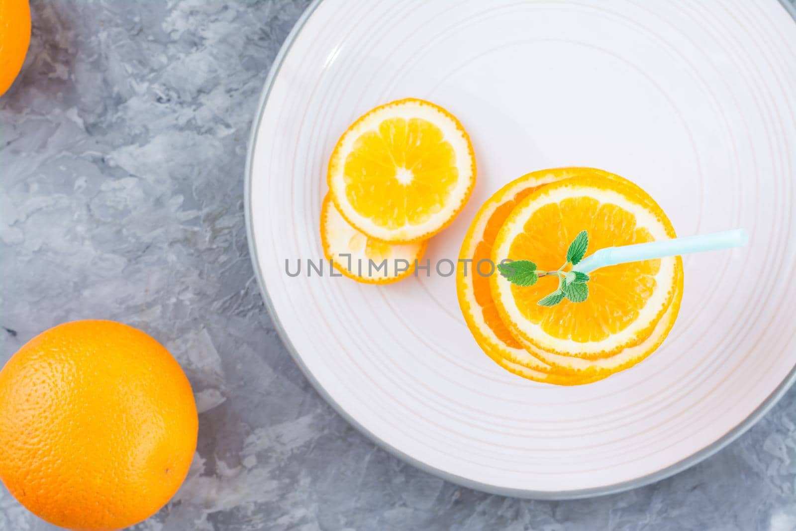 Fresh orange slices in a stack, mint leaves and a straw for a drink. Simulated orange juice. Top view