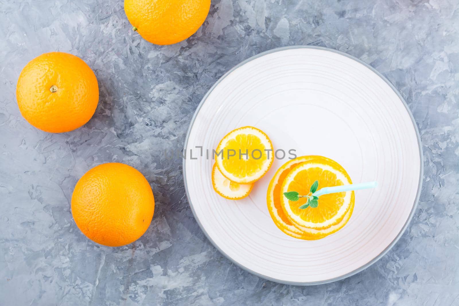 Fresh orange slices in a stack, mint leaves and a straw for a drink. Simulated orange juice. Top view. Healhy eating