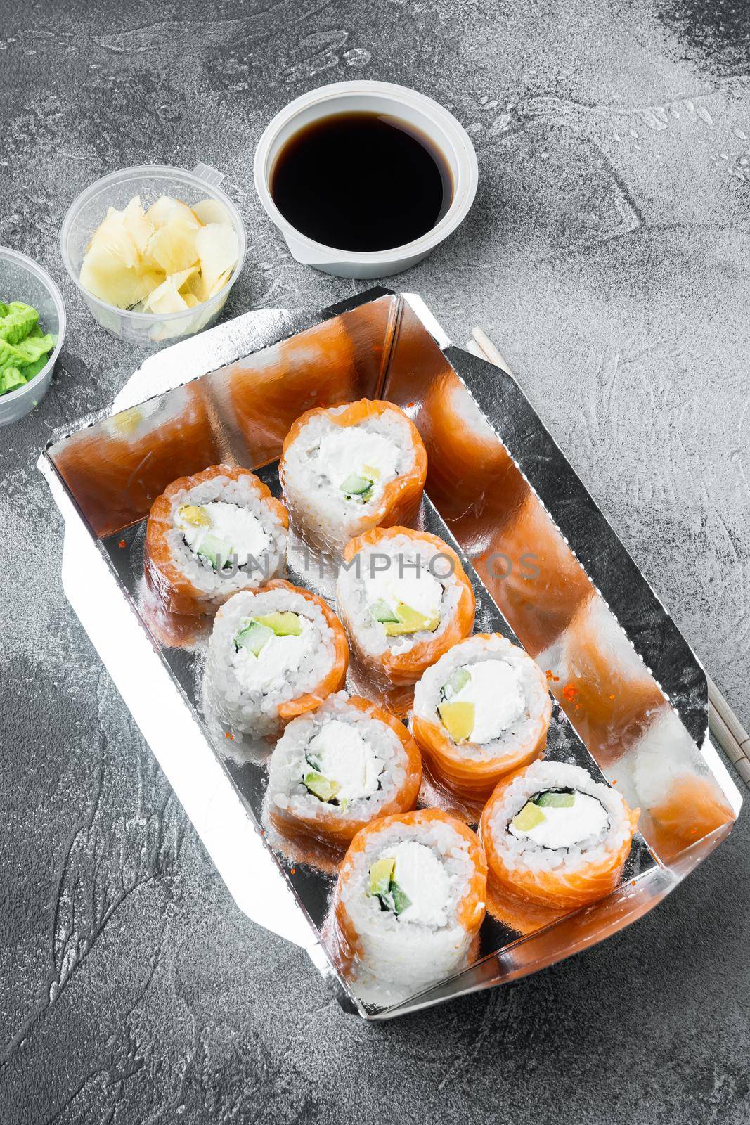 Variety of different sushi and rolls fro, salmon and tuna in delivery food concept, on gray stone background by Ilianesolenyi