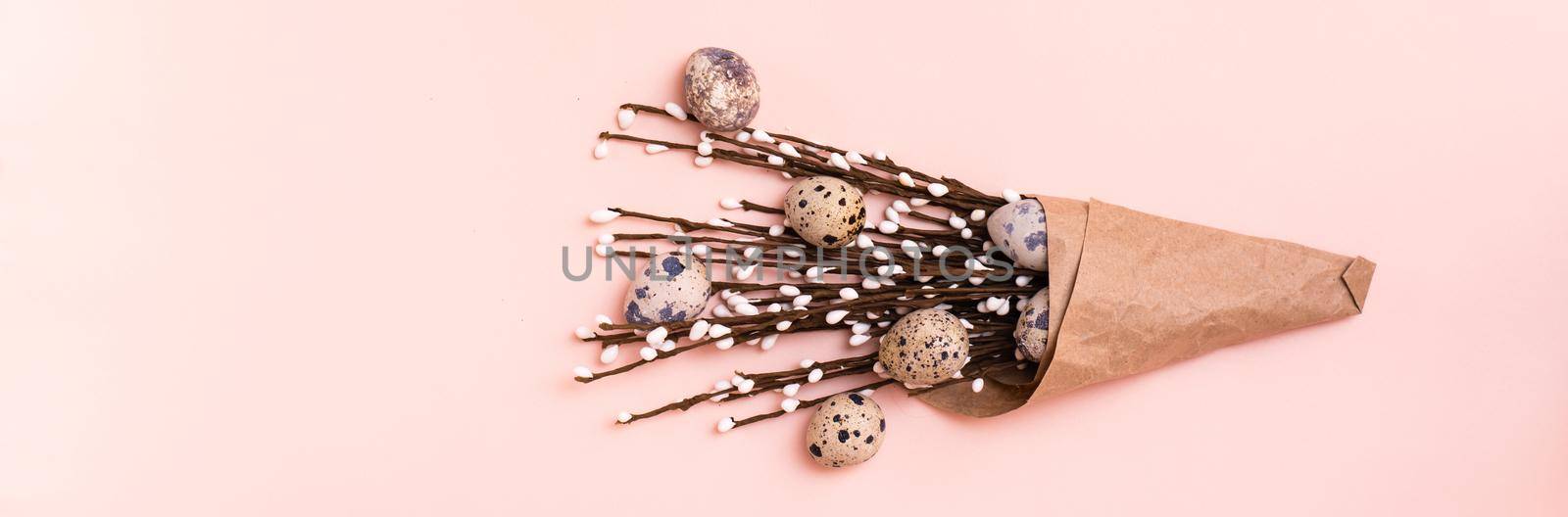 Happy Easter. Bouquet of quail eggs and pussy willow branches wrapped in brown paper on pink background. Web banner by Aleruana