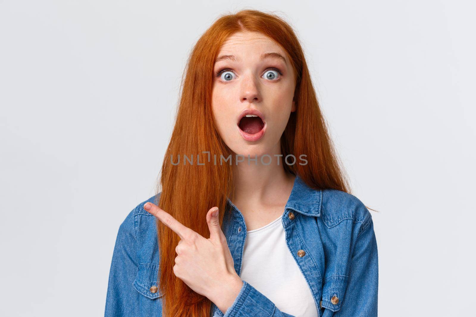 Close-up portrait impressed shook and speechless pretty redhead female student, teenager pointing upper left corner drop jaw, discussing amazing banner, product advertisement, white background.