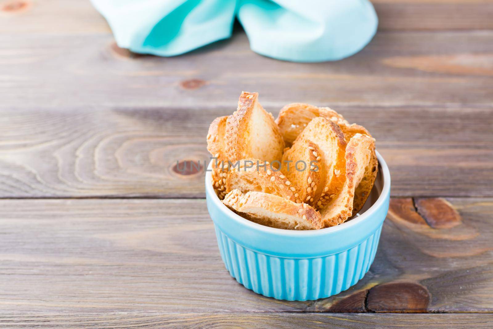 Small baguette toast in a bowl on a wooden table. Copy space