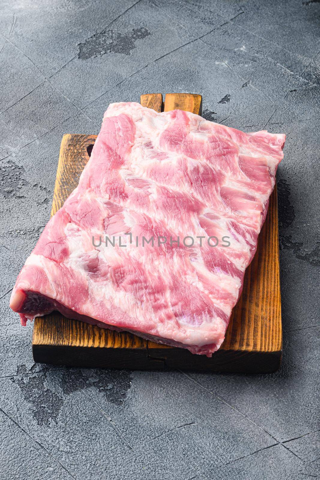 Pork rib, on wooden cutting board, on gray stone background by Ilianesolenyi