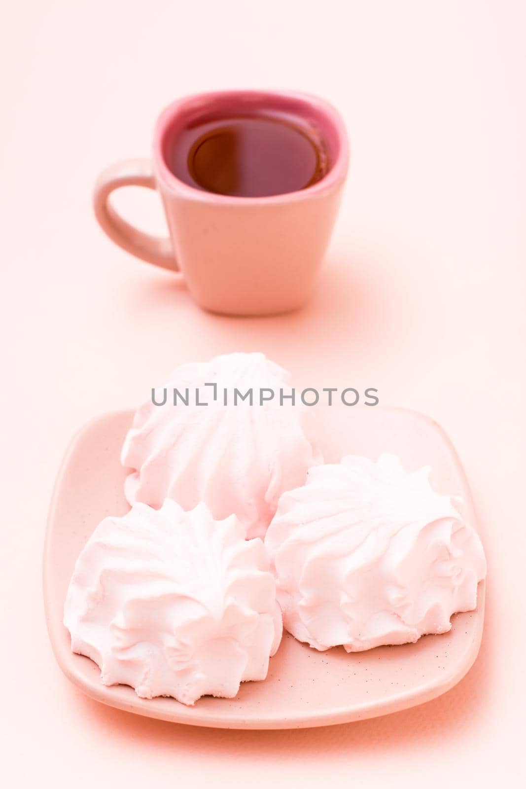 The concept is pink. Pink drink in a coffee cup and marshmallows on a saucer on a pink background. Vertical view by Aleruana