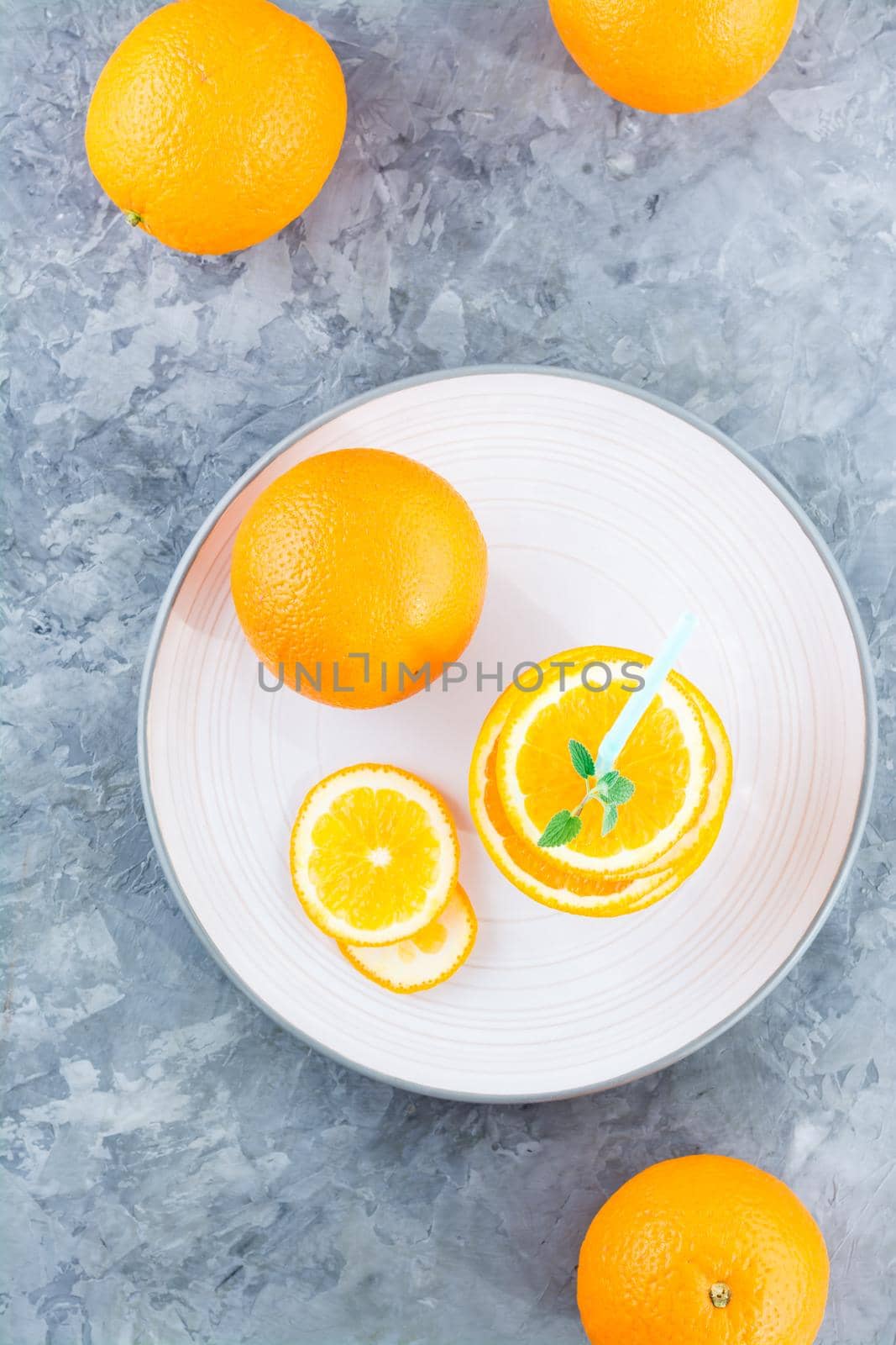 Fresh orange slices in a stack, mint leaves and a straw for a drink. Simulated orange juice. Top and vertical view. Healhy eating by Aleruana