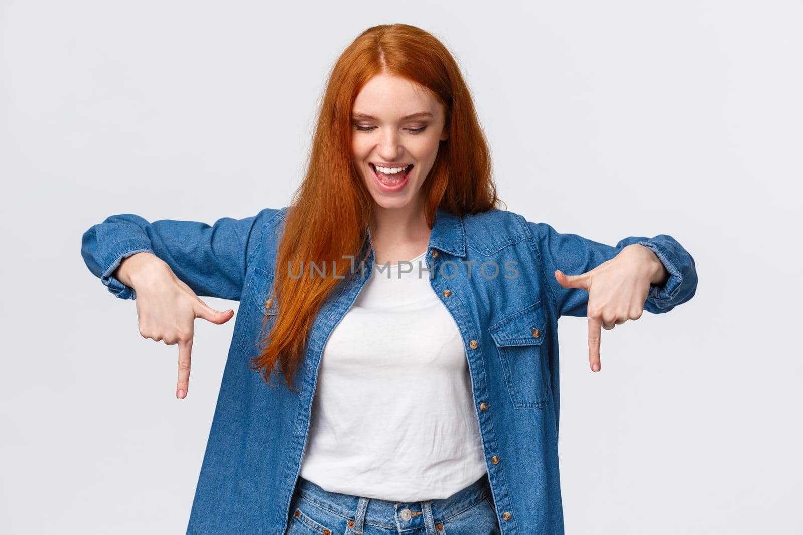 Excited, joyful good-looking redhead woman having fun on party, checking out view from top, showing product, checking out awesome new sound system friends house, pointing looking down, smiling.