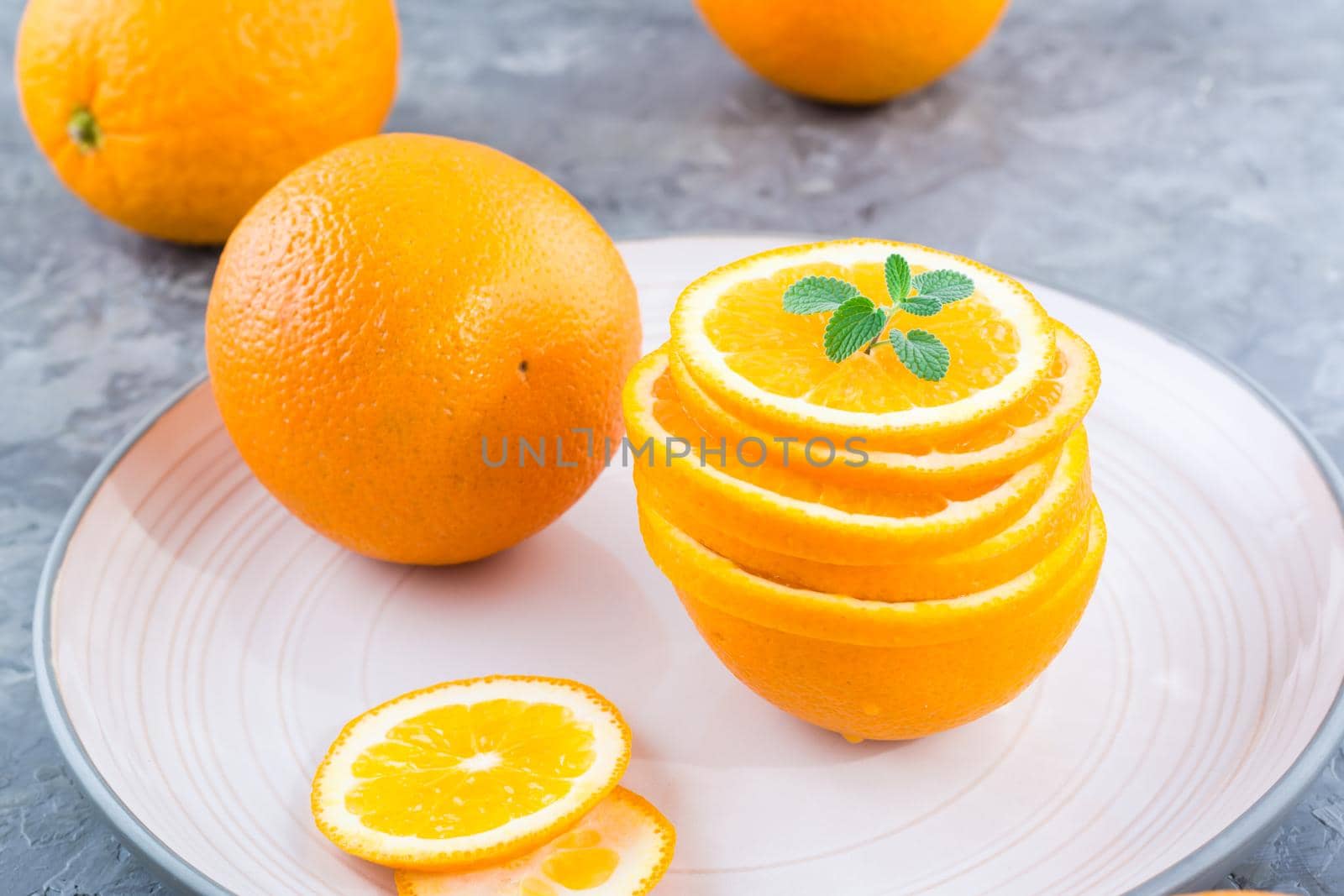 Fresh orange slices in a stack and mint leaves on a plate on the table. Healthy eating by Aleruana