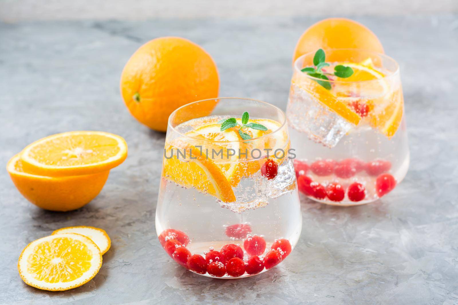 Hard seltzer cocktail with orange, cranberry and mint in glasses on the table. Alcoholic beverage