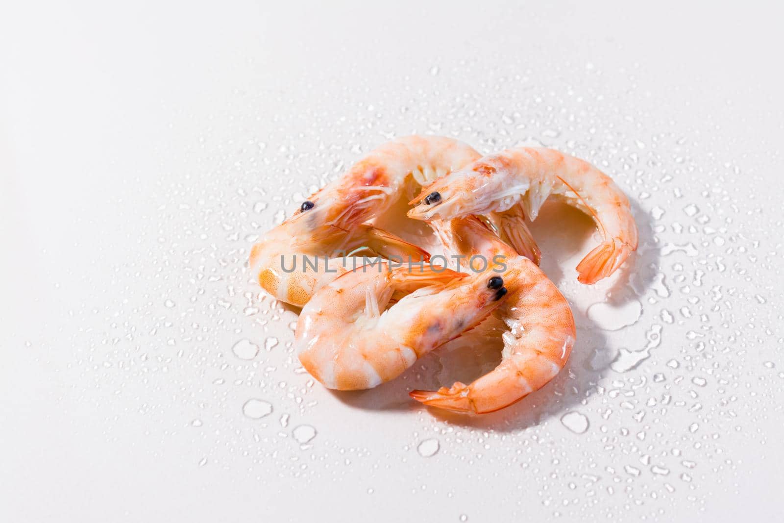 Raw thawed prawns with water drops on a pink background. Mediterranean food. Hard light by Aleruana