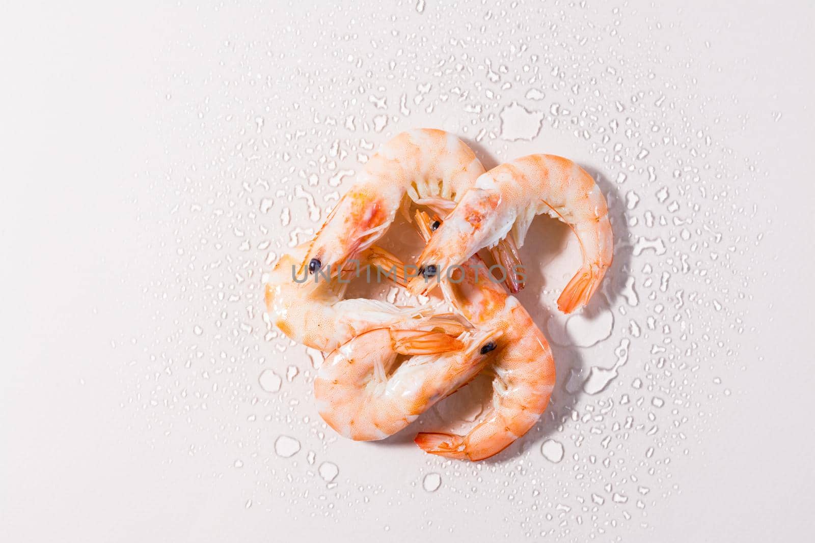 Raw thawed prawns with water drops on a pink background. Mediterranean food. Hard light. Top view by Aleruana