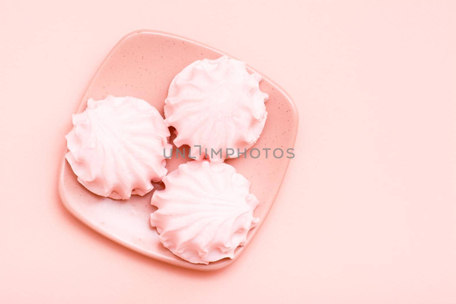 The concept is pink. Pink marshmallows on a saucer on a pink background. Top view by Aleruana