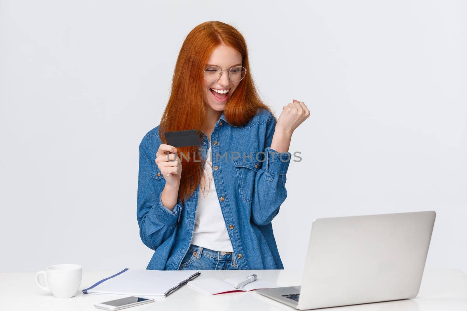 Satisfied, excited and triumphing good-looking redhead girl fist pump, bought thing with good discount, say yes celebrating, shopping online, holding credit card, won bonuses, white background.