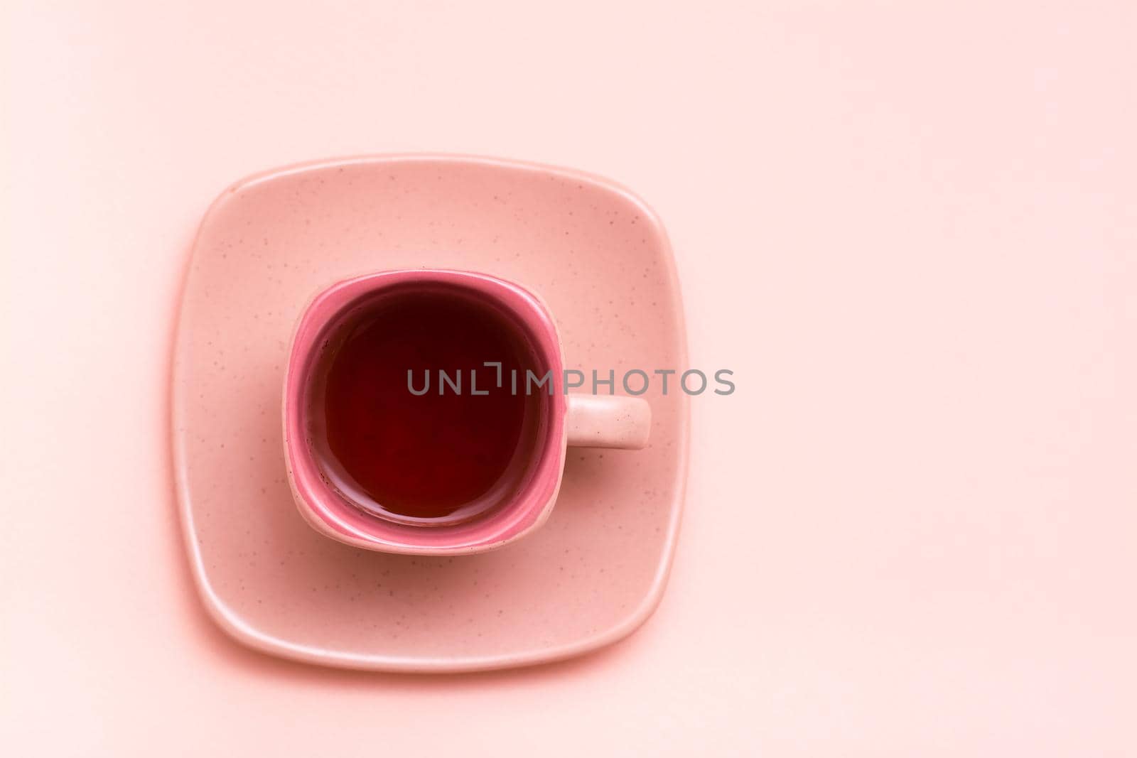 Pink concept. Square coffee cup with a pink drink on a saucer on a pink background. Top view