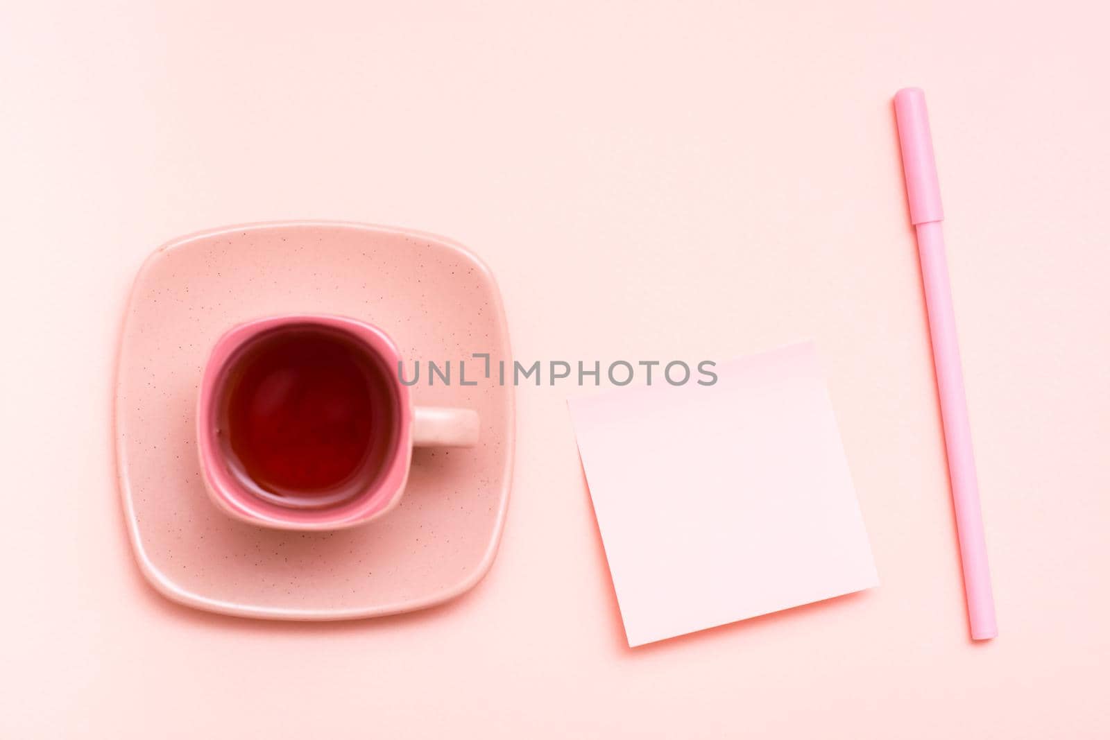 The concept is pink. Pink drink in a coffee cup, writing sheet and pen on a pink background. Top view by Aleruana