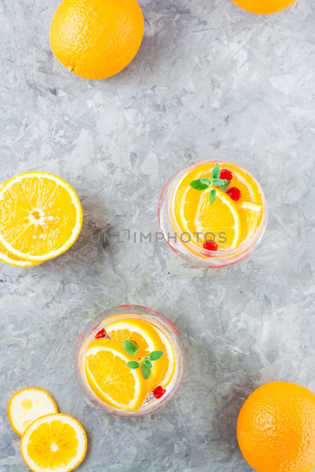 Hard seltzer cocktail with orange, cranberry and mint in glasses and cut oranges on the table. Alcoholic beverage. Vertical and top view