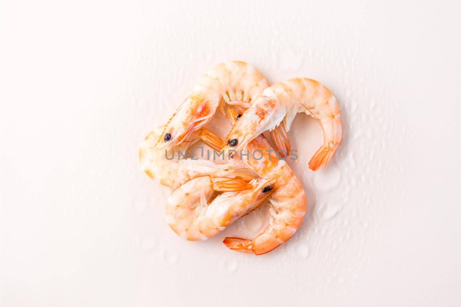 Raw thawed prawns with water drops on a pink background. Mediterranean food. Top view