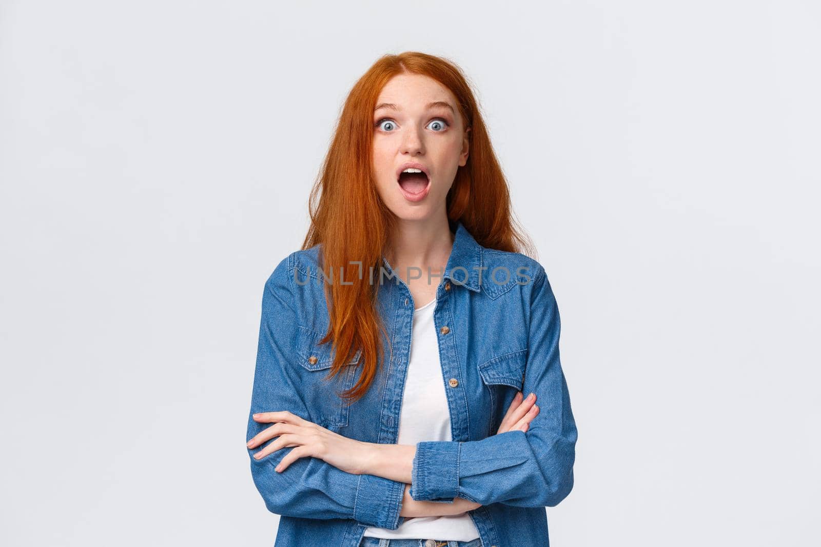 Omg, no way, unbelievable. Impressed and surprised, curious redhead girl dropping jaw from amazement, lose speech, staring astonished, standing astounded, found out awesome news, white background.