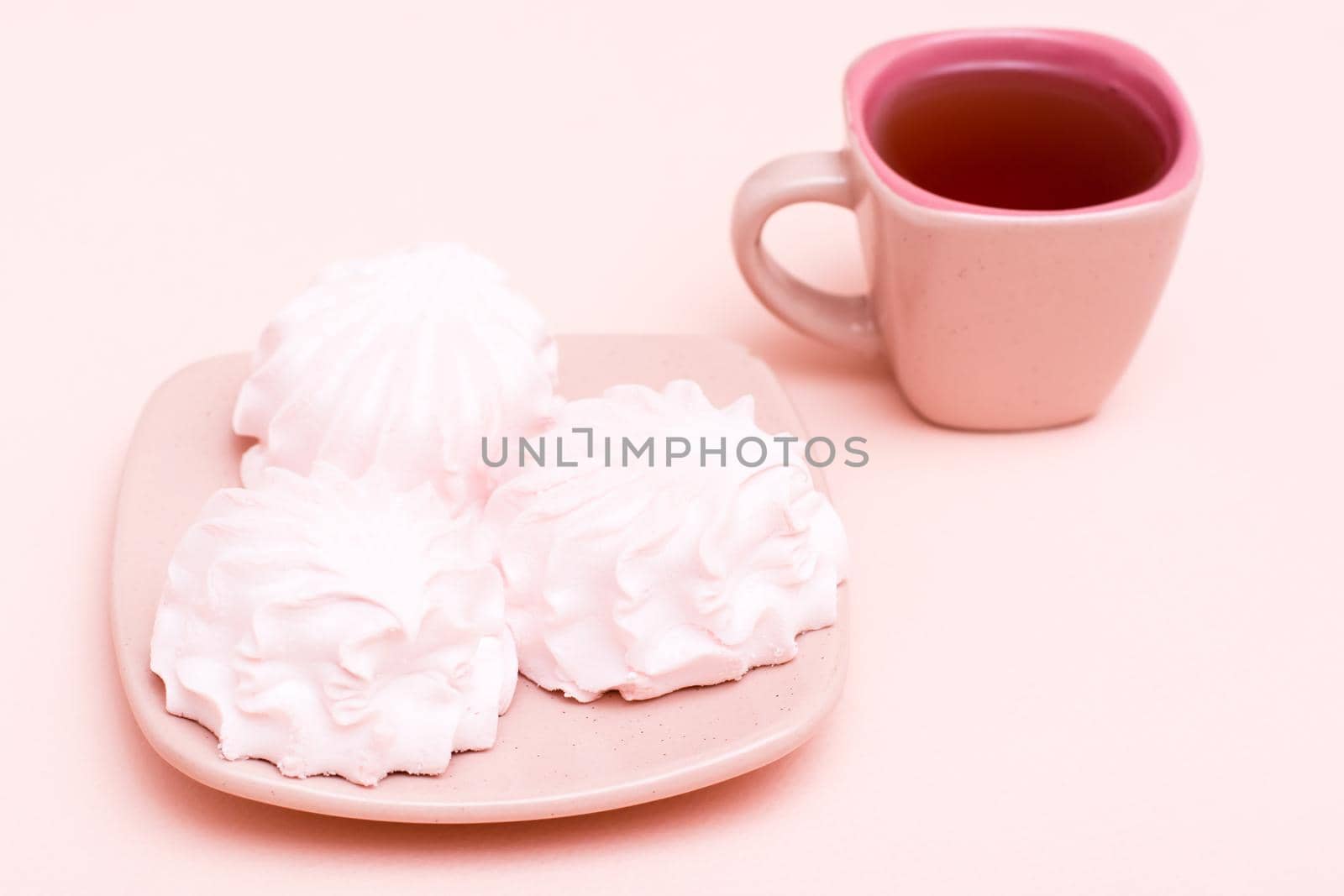 The concept is pink. Pink drink in a coffee cup and marshmallows on a saucer on a pink background. Copy space