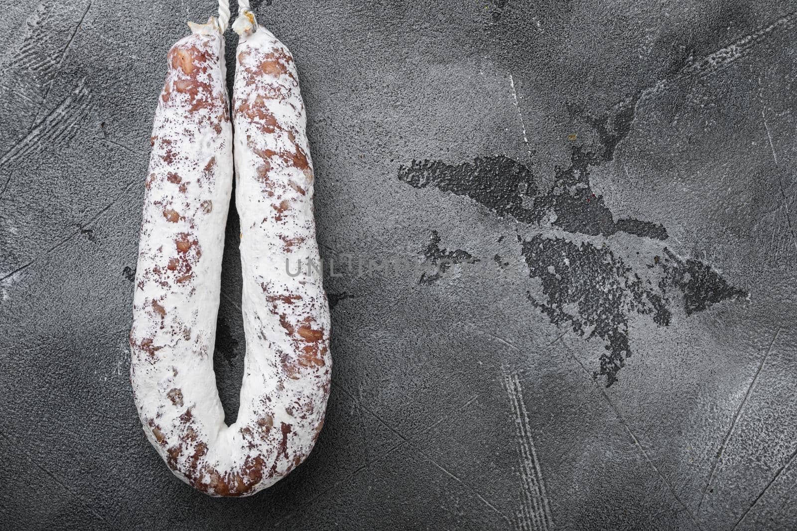 Dry cure salami sausage fuet on grey background, topview with space for text.