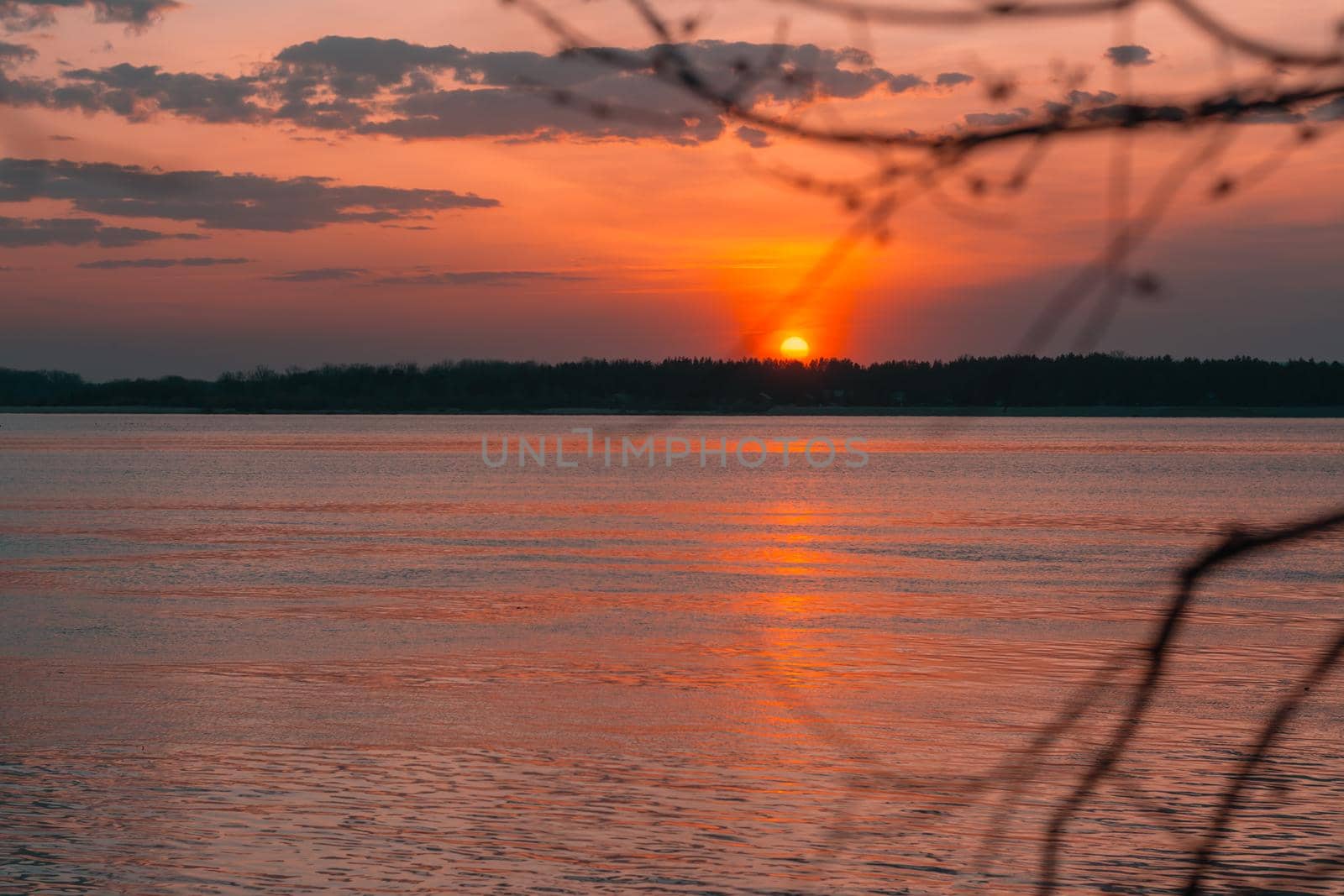 Sunset on the river on a summer evening. Calm water in the orange rays of the sun. Local tourism by Aleruana