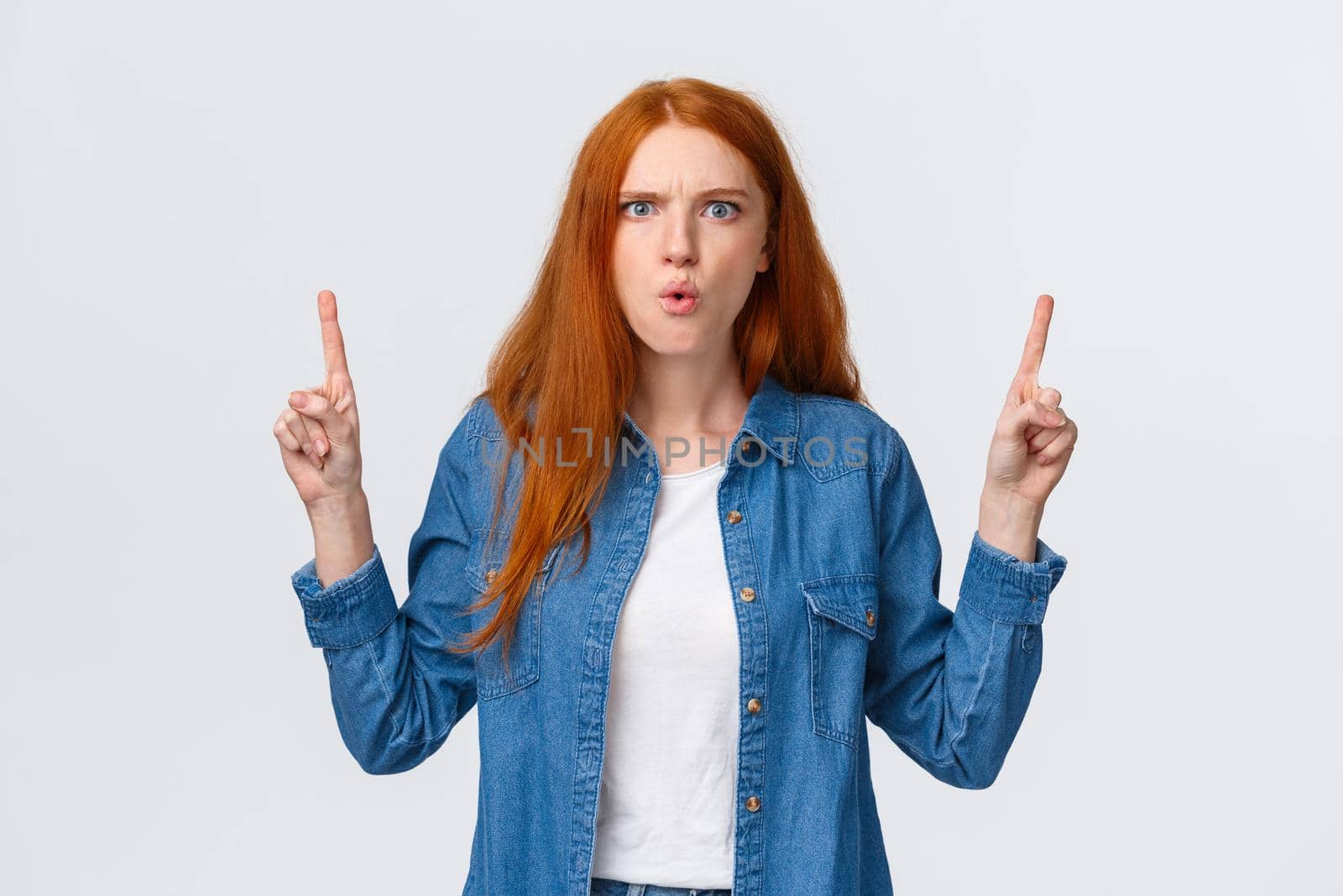 Frustrated and mad girlfriend want hear explanations, demand answer. Perplexed and angry tensed redhead woman speaking to friend frowning and pointing fingers up, white background.