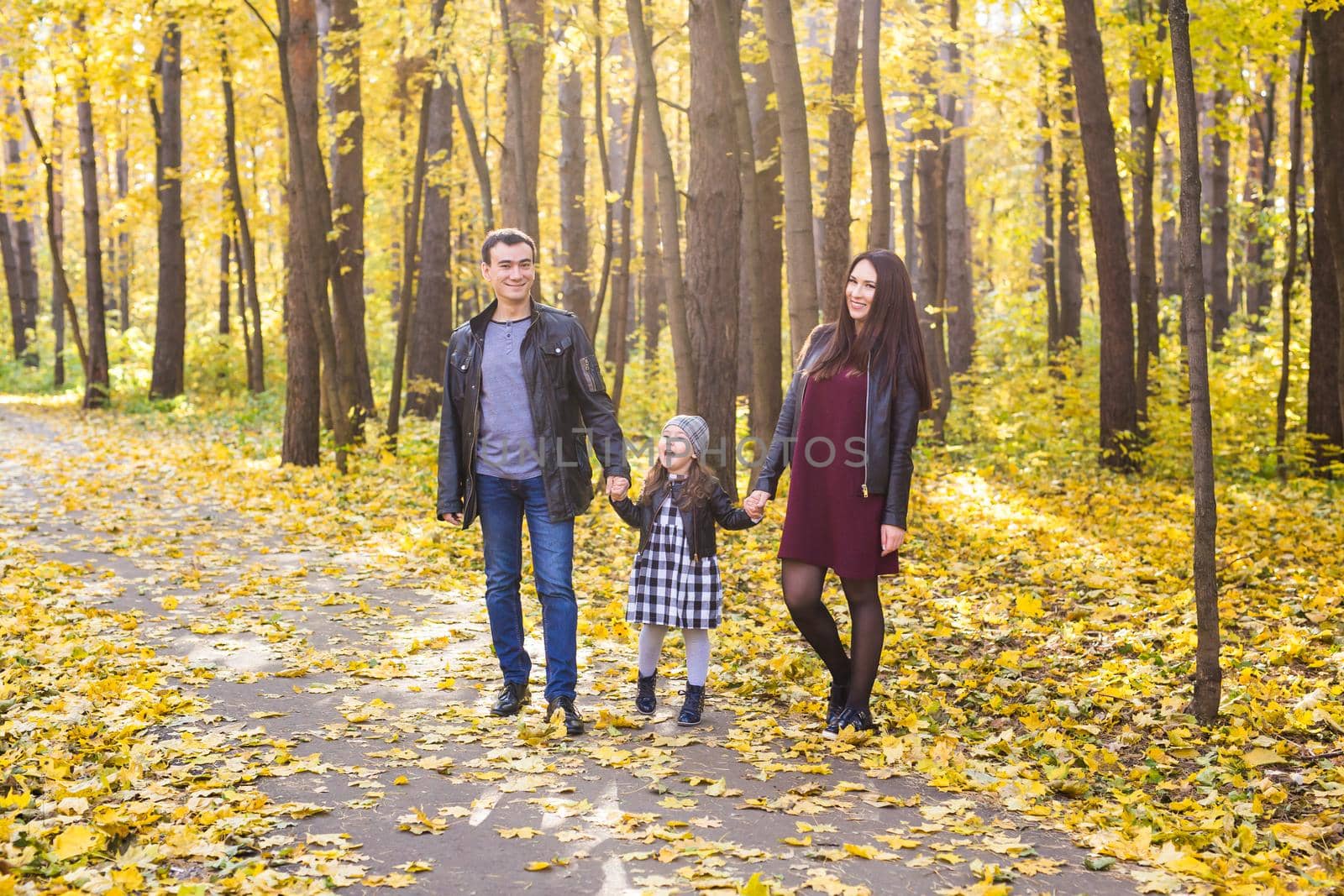 People, family and leisure concept - family standing in autumn park having fun.