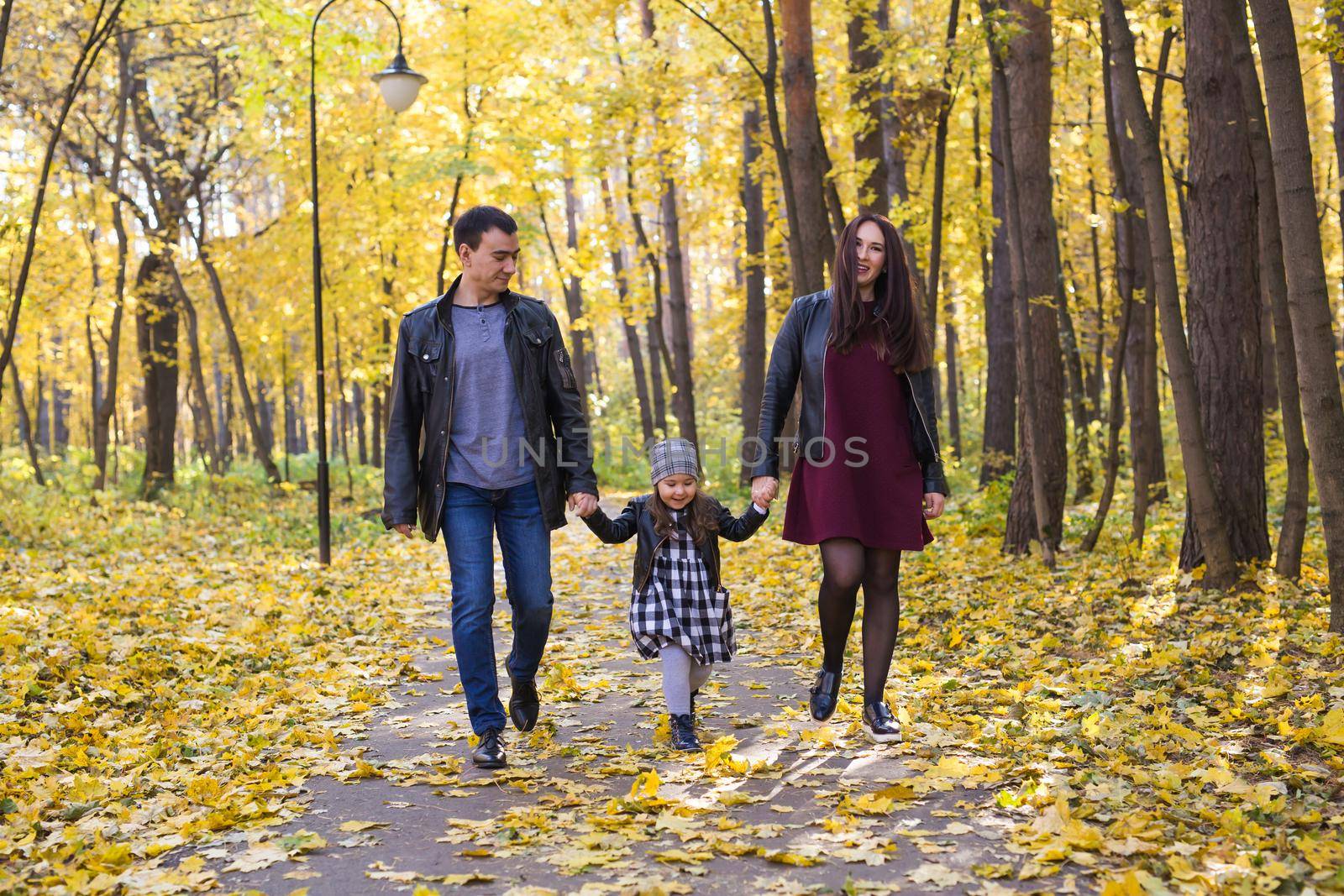 People, family and leisure concept - mixed race father and mother have fun in autumn park with their daughter by Satura86
