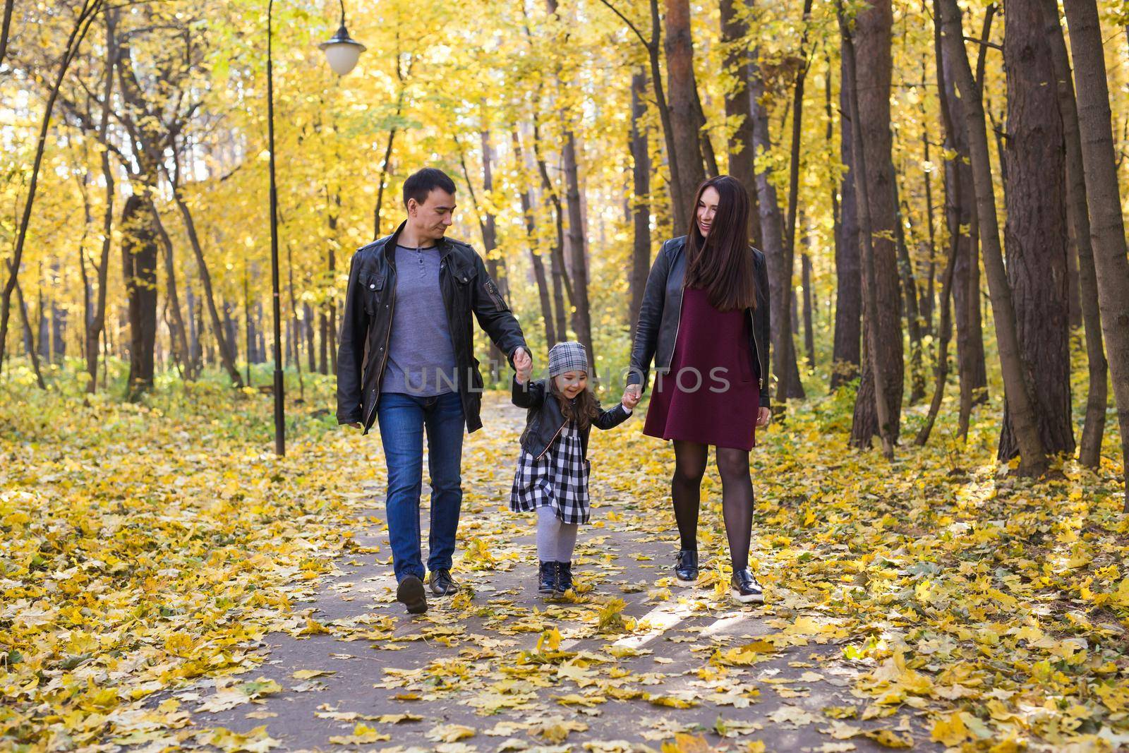 people, family and leisure concept - family with a young daughter walking in autumn park by Satura86