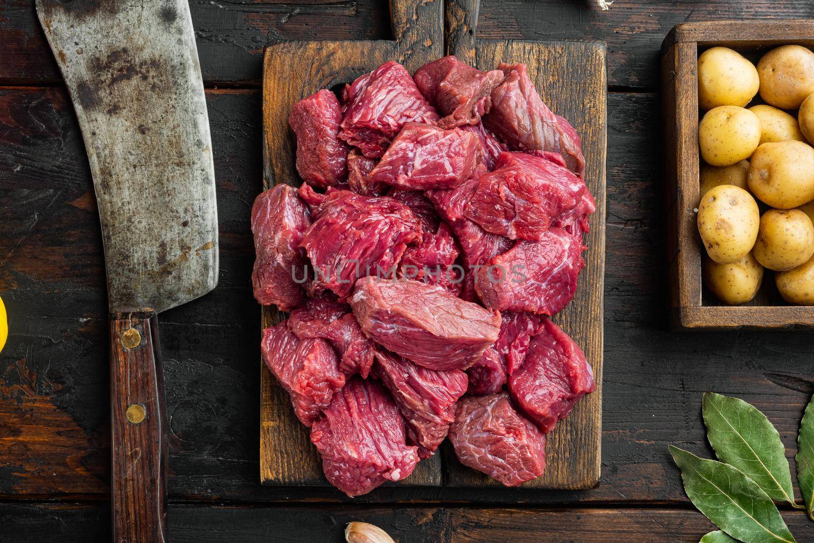 Raw meat diced for stew set and potatoe, on old dark wooden table, top view flat lay