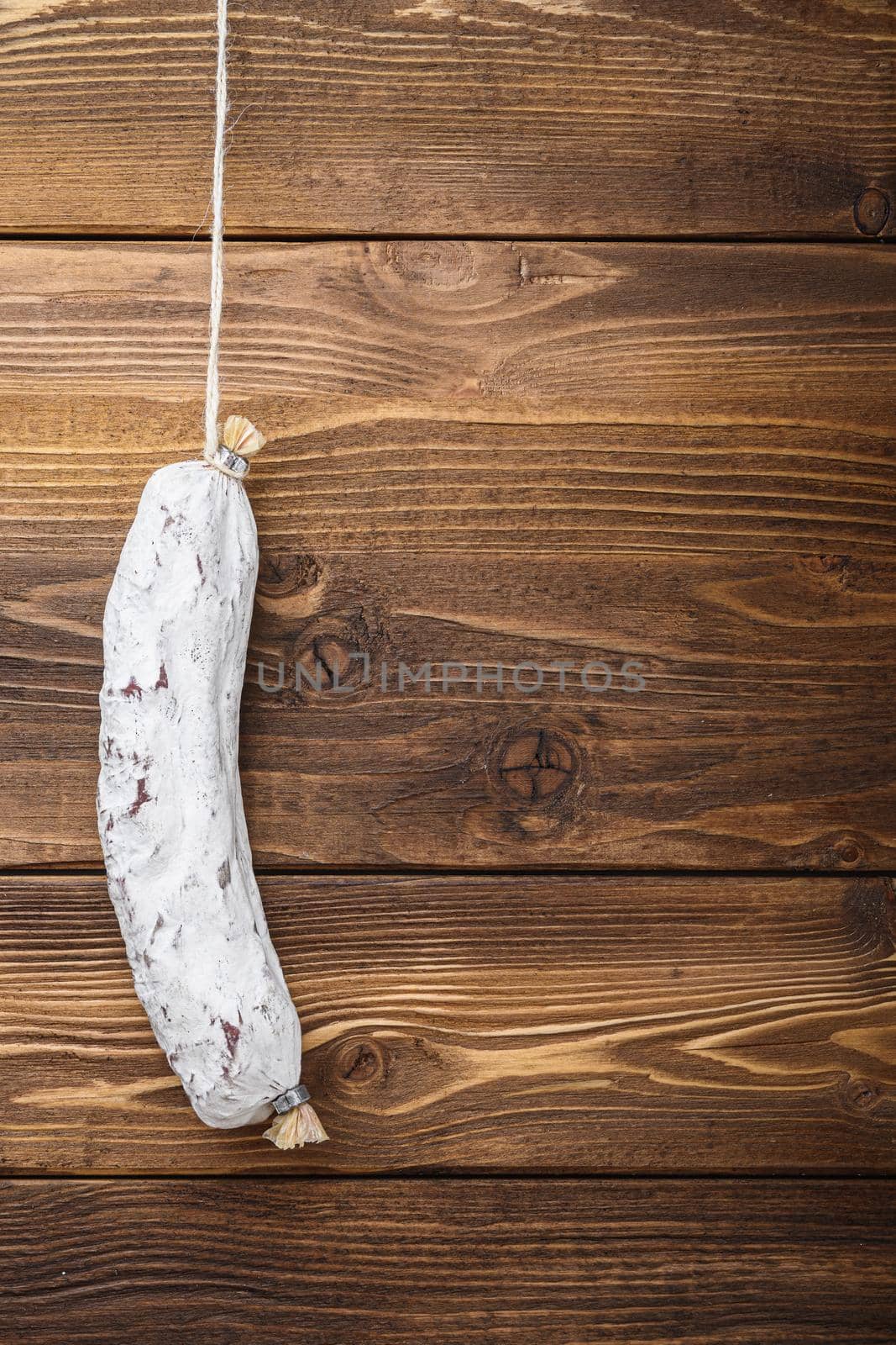 Salchichon sausage on light wooden background, top view with copy space.